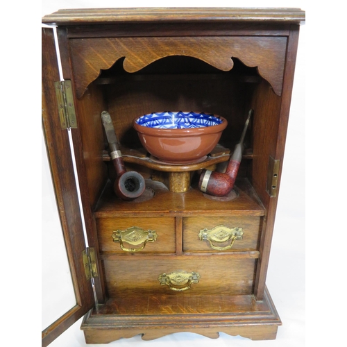 34 - Edwardian oak cased smokers cabinet with glazed door, interior fitted with drawers and pipe holders