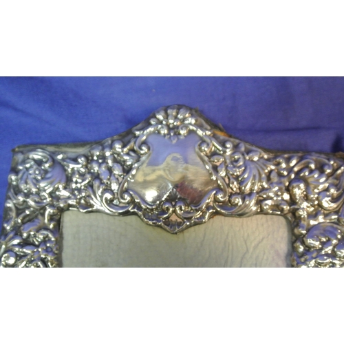 191 - London silver double photograph frame, hinged, and with ornate scroll and foliate decoration. H 22 X... 