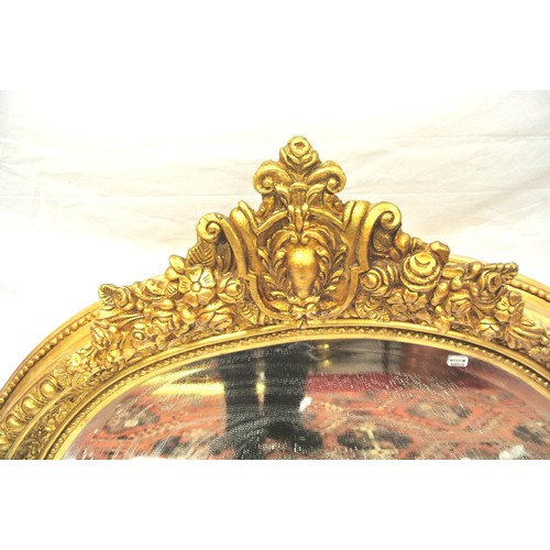 134 - Regency style oval gilt framed wall mirror with scroll & foliate pediment and ornate frame