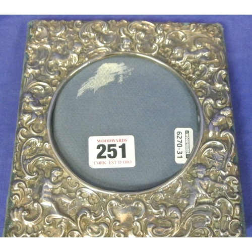 251 - Irish Silver photo frame repousse with swags, scrolls & putti, round centre, dated 1990