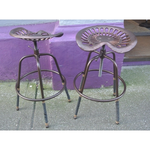 296 - Pair of cast iron tractor seats mounted as stools with swivel tops