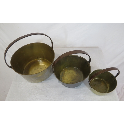 97 - Three round brass pots of graduating sizes with shaped handles