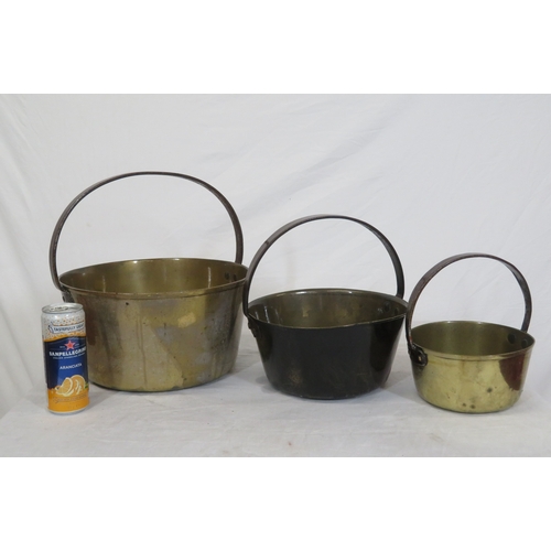 97 - Three round brass pots of graduating sizes with shaped handles