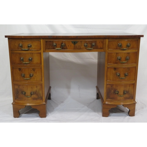 145 - Edwardian style serpentine fronted yew pedestal desk with shaped drawers, brass drop handles, on bra... 