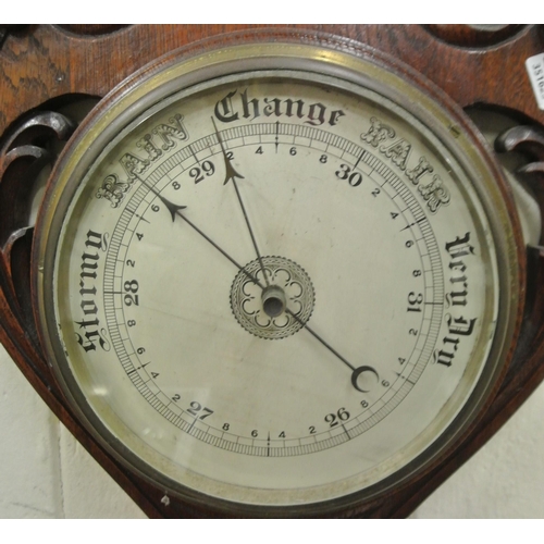 217 - Edwardian oak wheel barometer with brass framed dial, thermometer and scroll carving