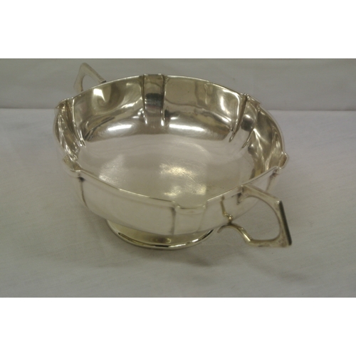 73 - Birmingham silver porringer with shaped panelled sides and handles, on raised round foot. H 5cm X L ... 