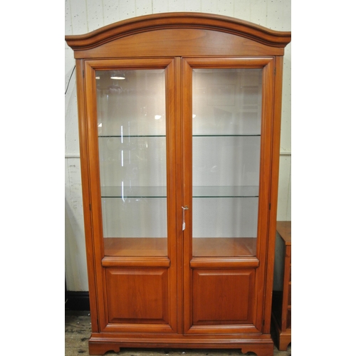 155 - Yew bookcase or display cabinet with serpentine top, glazed doors and shelving, on bracket feet