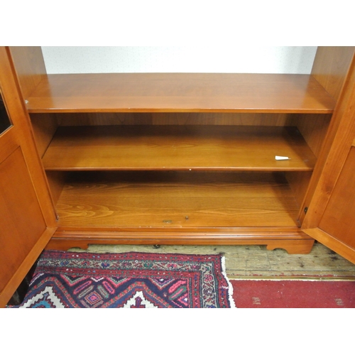 155 - Yew bookcase or display cabinet with serpentine top, glazed doors and shelving, on bracket feet