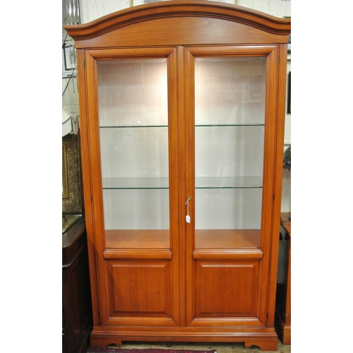 155 - Yew bookcase or display cabinet with serpentine top, glazed doors and shelving, on bracket feet