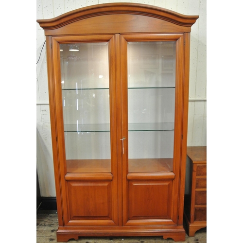 80 - Yew bookcase or display cabinet with serpentine top, glazed doors and shelving, on bracket feet