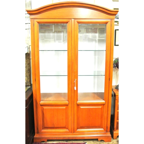 80 - Yew bookcase or display cabinet with serpentine top, glazed doors and shelving, on bracket feet