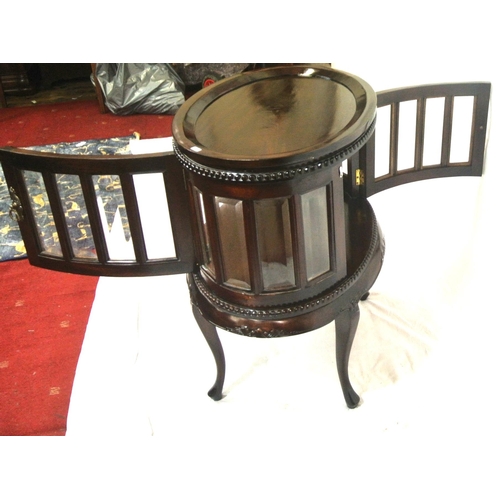 175 - Butlers oval drinks cabinet with detachable tray, bevelled glazed panels, brass drop handle, on cabr... 