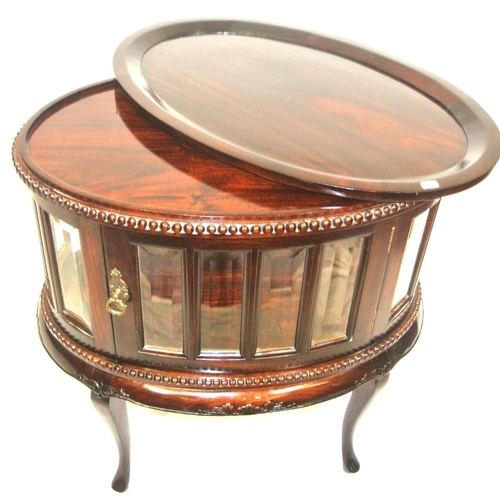 175 - Butlers oval drinks cabinet with detachable tray, bevelled glazed panels, brass drop handle, on cabr... 