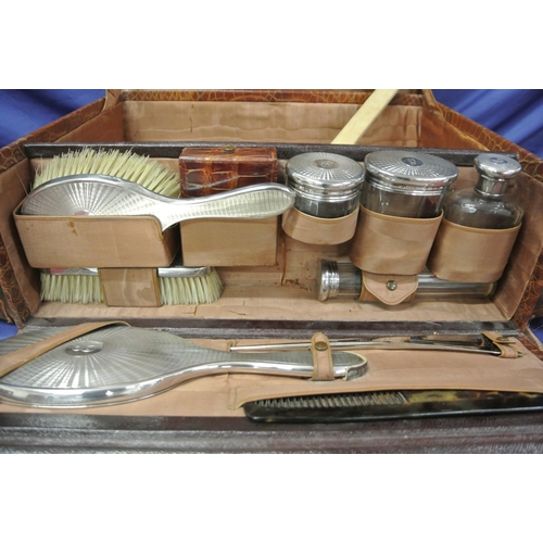 102 - Vintage crocodile lined travel suitcase with silver topped brushes and bottles inset