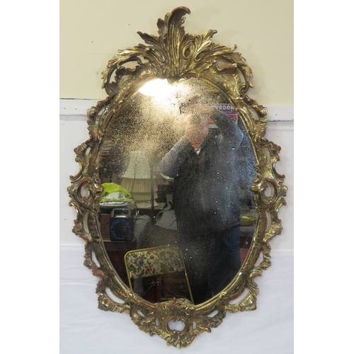 174 - Regency design carved timber gilded oval mirror with ornate scroll & foliate decoration 115 x70cm