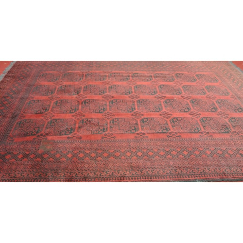 179 - Rich red ground Afghan double knot carpet with traditional Bokhara design, with elephant footprint d... 