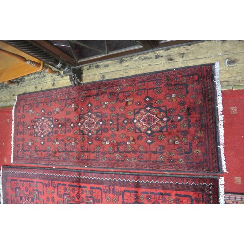 261 - Two rich red ground full pile Afghan Tubi runners with bespoke Bokhara design. 150 x54 cm each