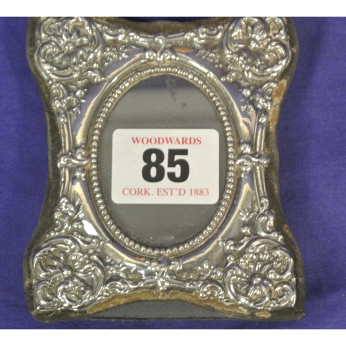 85 - Small London silver photograph frame with oval ope and ornate embossed decoration.H9 X 8CM