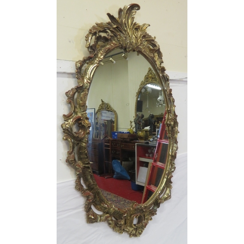 343 - Regency design carved timber gilded oval mirror with ornate scroll & foliate decoration 115 x70cm