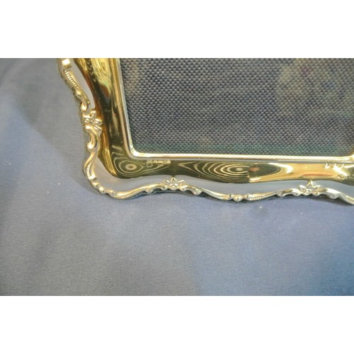 55 - Large English silver photograph frame with shaped floral decorated border. 27x20cm. To fit 18x13cm