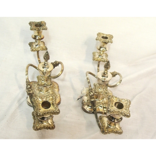 15 - Pair of silverplated candleabrae with shaped arms and foliate decorated sconces and shaped bases