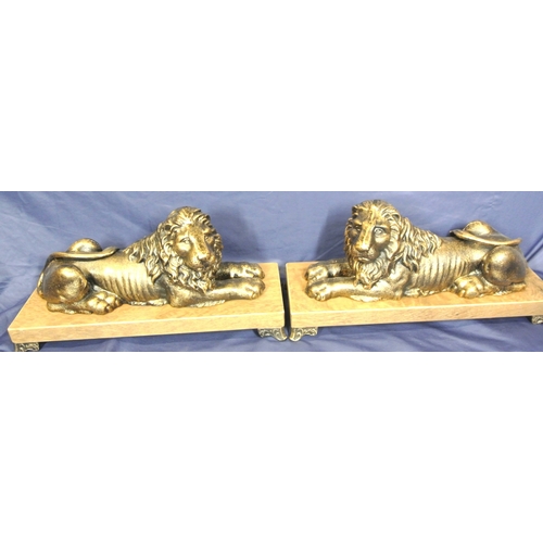 247 - Pair of ornate gilded reclining lions on oblong timber plinths with shaped legs