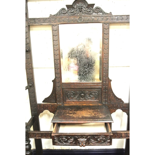 125 - Arts & Crafts oak hallstand with scroll and figured decoration, mirror inset, glove drawer, and turn... 