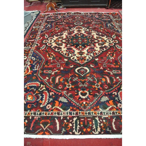 146 - Rich red and blue ground Persian Baktia village carpet with central medallion, 295x200cm