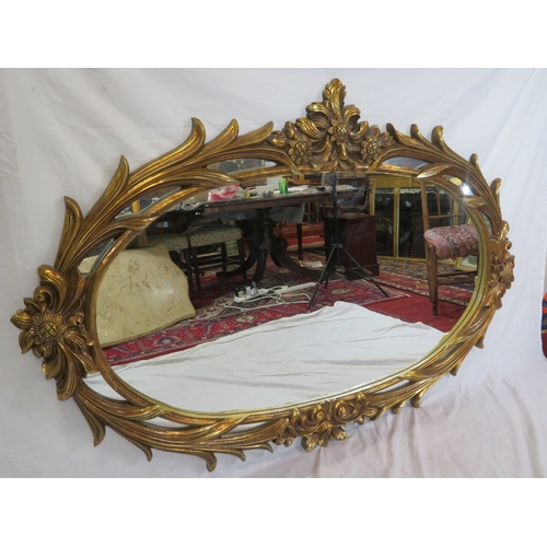 462 - Large ornate oval gilt mirror in scroll & foliate decorated frame, 180 x120 cm