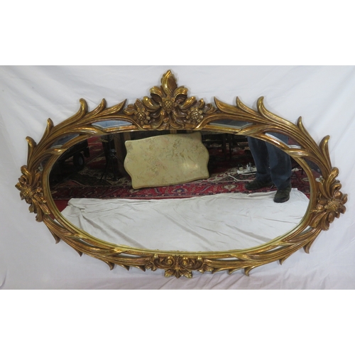 462 - Large ornate oval gilt mirror in scroll & foliate decorated frame, 180 x120 cm
