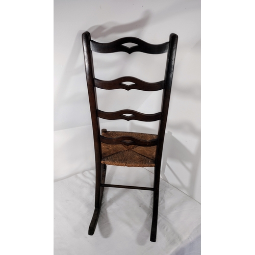 69 - Antique Ladderback Rocking Chair with Woven Rush Seat, Featuring Curved Back Rails and Rustic Wooden... 