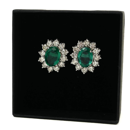 10 - A PAIR OF 18CT WHITE GOLD OVAL EMERALD AND DIAMOND CLUSTER STUD EARRINGS. 
(Emeralds 3.15ct, Diamond... 