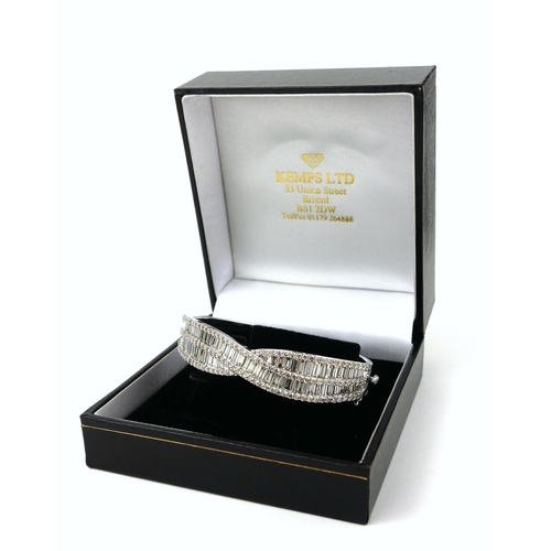 36 - AN IMPRESSIVE LARGE 9CT WHITE GOLD TWIST STYLE DIAMOND BANGLE, SET WITH BAGUETTE CUT AND ROUND BRILL... 