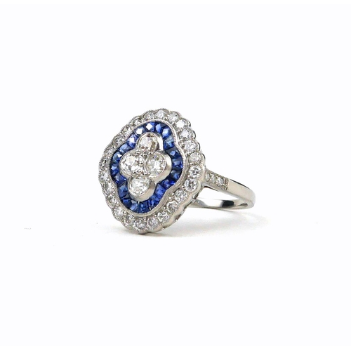 35 - A PLATINUM, SAPPHIRE AND DIAMOND RING.  
The 4 central diamonds surrounded by calibre cut sapphires ... 