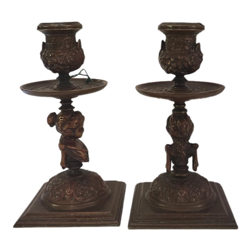 166 - A PAIR OF 19TH CENTURY CONTINENTAL PATINATED BRONZE CHAMBER CANDLESTICKS
Each column cast with a bus... 