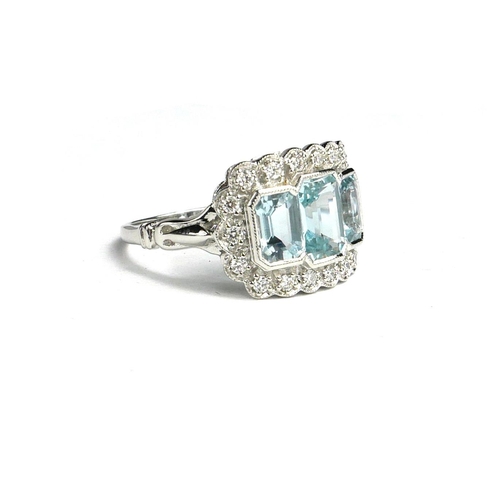 28 - AN 18CT WHITE GOLD AND THREE STONE EMERALD CUT AQUAMARINE AND ROUND CUT DIAMOND CLUSTER DRESS RING.
... 