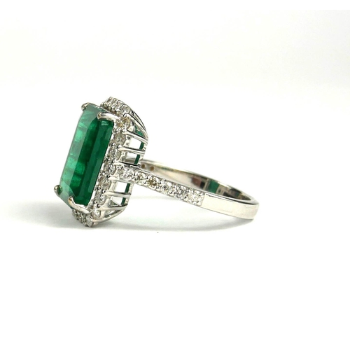 81A - AN 18CT WHITE GOLD LARGE EMERALD CUT EMERALD AND ROUND BRILLIANT CUT DIAMOND CLUSTER RING with diamo... 