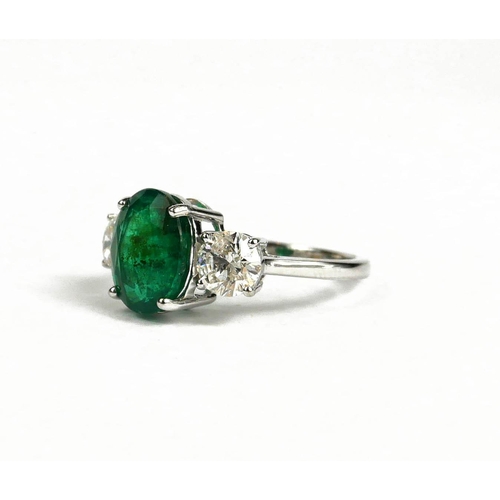 83A - AN 18CT WHITE GOLD OVAL EMERALD AND DIAMOND THREE STONE RING.  (Emerald 3.75ct.  Diamonds 1.41ct)