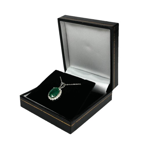 99A - AN 18CT WHITE GOLD OVAL EMERALD AND DIAMOND CLUSTER PENDANT on an 18