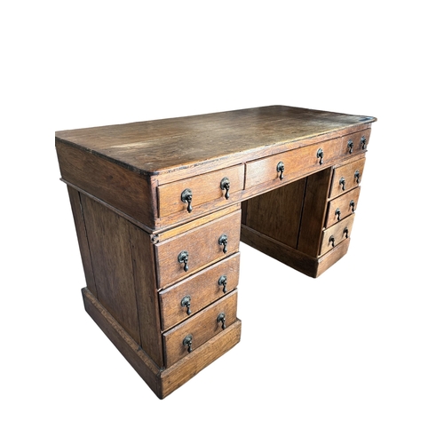 249 - A 19TH CENTURY VICTORIAN OAK PEDESTAL DESK 
Having an arrangement of nine drawers, raised on a plint... 