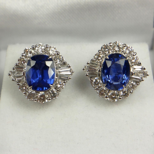 79B - A PAIR OF 18CT WHITE GOLD, OVAL BLUE SAPPHIRE AND DIAMOND CLUSTER STUDS.  
(BS 4.49CT.  DIAMONDS 1.8... 