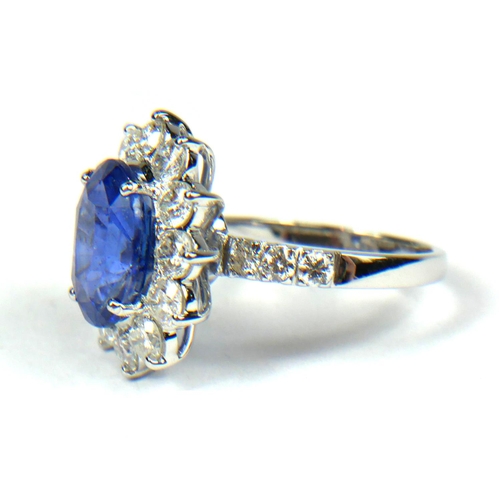 83B - AN 18CT WHITE GOLD, OVAL SAPPHIRE AND ROUND BRILLIANT CUT DIAMOND CLUSTER RING, flanked with diamond... 