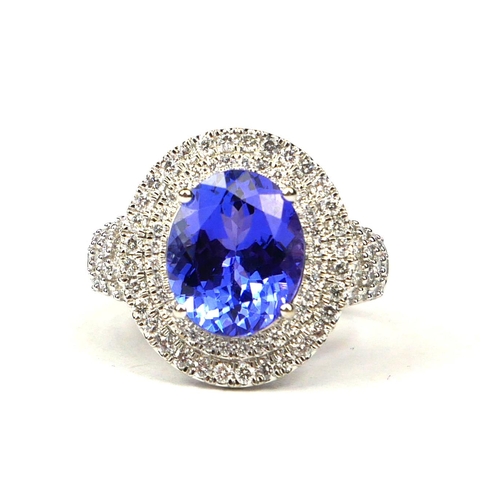 6A - AN 18CT WHITE GOLD LARGE OVAL TANZANITE & DIAMOND RING,
The tanzanite surrounded by a double halo of... 