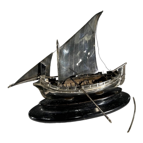 26 - A MID 20TH CENTURY MALTESE SILVER MODEL OF A BOAT 
On an ebonised stand, having two rowing oars. 
(h... 