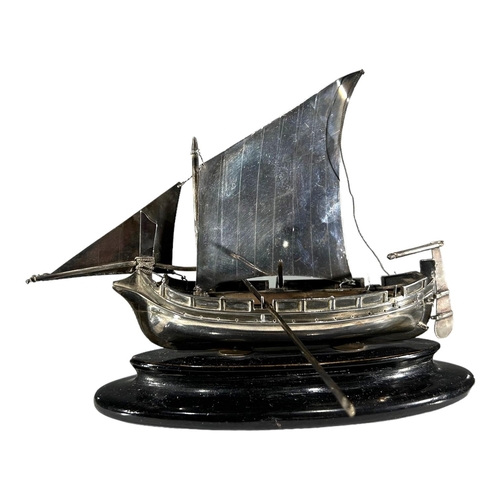 26 - A MID 20TH CENTURY MALTESE SILVER MODEL OF A BOAT 
On an ebonised stand, having two rowing oars. 
(h... 