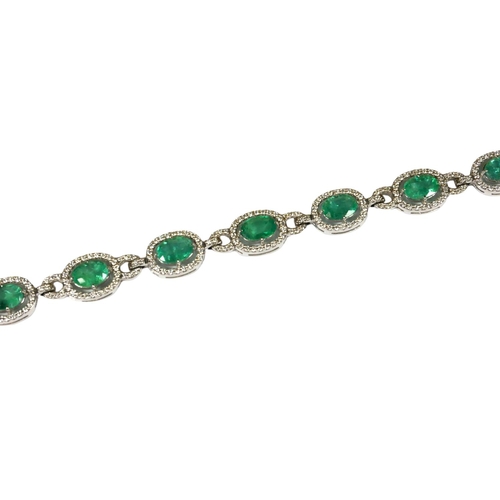 21 - AN 18CT WHITE GOLD, EMERALD AND DIAMOND LINE BRACELET, boxed.
(Approx oval emeralds 7.12ct total, Di... 