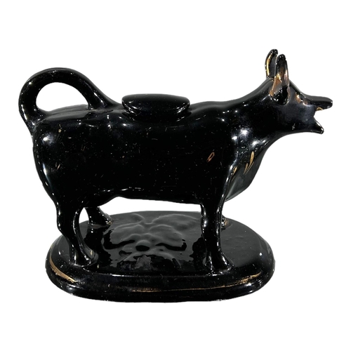 53 - A VICTORIAN JACKFIELD BLACK AND GOLD COW CREAMER. TOGETHER WITH DELFT BLUE AND WHITE COW CREAMER. 
(... 