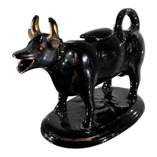 53 - A VICTORIAN JACKFIELD BLACK AND GOLD COW CREAMER. TOGETHER WITH DELFT BLUE AND WHITE COW CREAMER. 
(... 