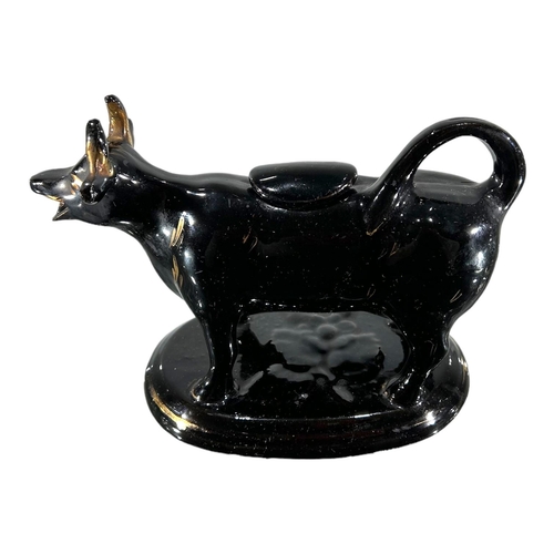 53 - A VICTORIAN JACKFIELD BLACK AND GOLD COW CREAMER. TOGETHER WITH DELFT BLUE AND WHITE COW CREAMER. 
(... 