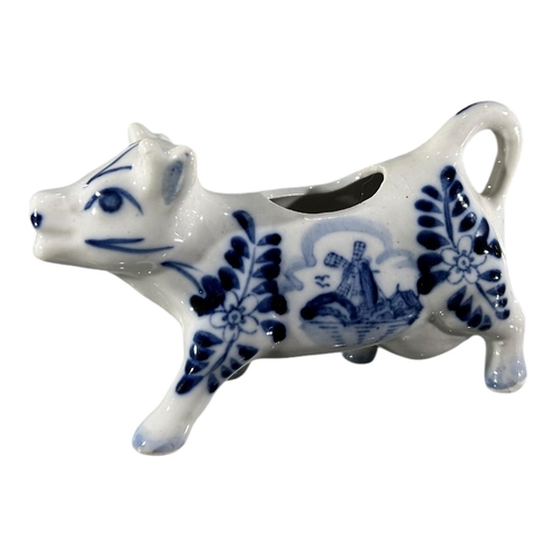 53 - A VICTORIAN JACKFIELD BLACK AND GOLD COW CREAMER. TOGETHER WITH DELFT BLUE AND WHITE COW CREAMER. 
(... 